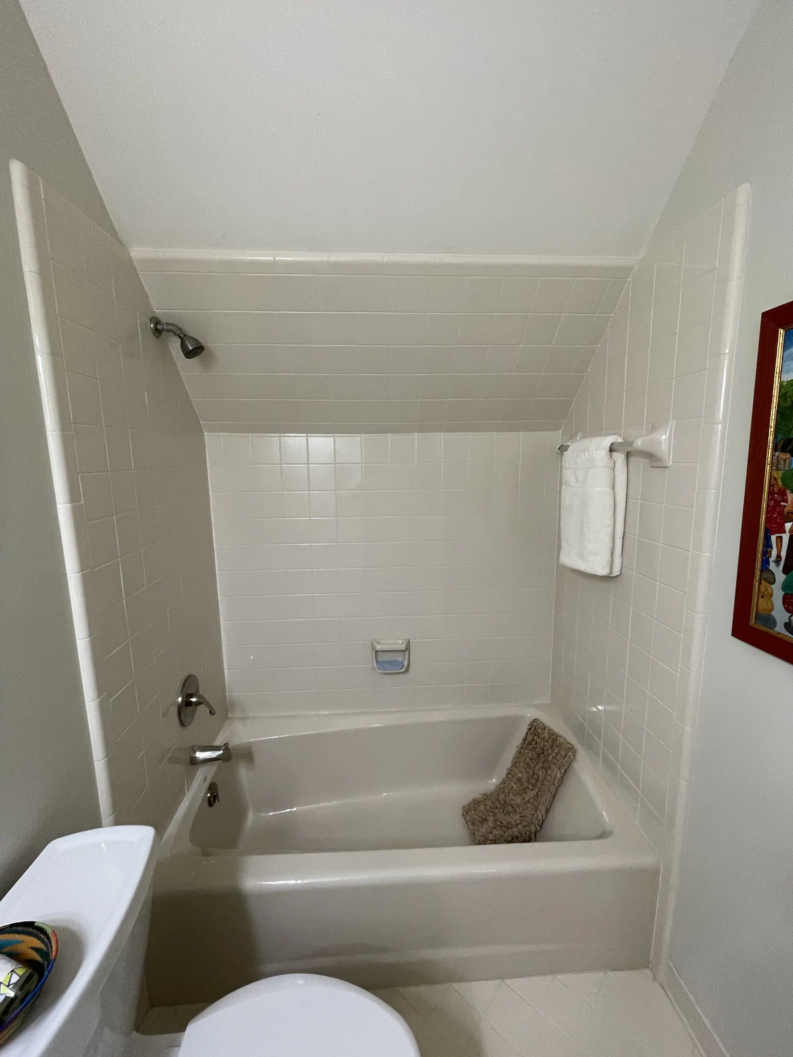 Before: Quail Hollow bathroom with white subway tile, an alcove tub, and a sloped-ceiling shower