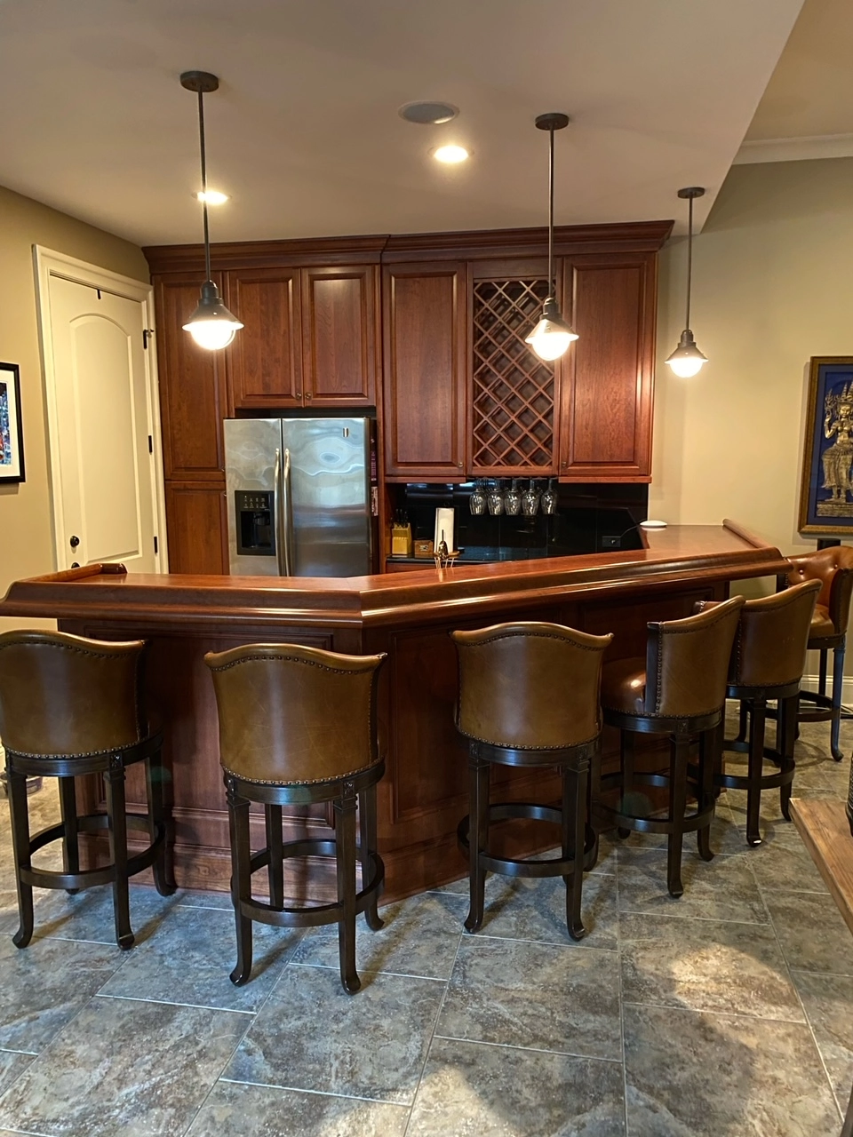 Basement wet bar with dark wood cabinets, a wine rack, and leather bar stools in Ballantyne Country Club
