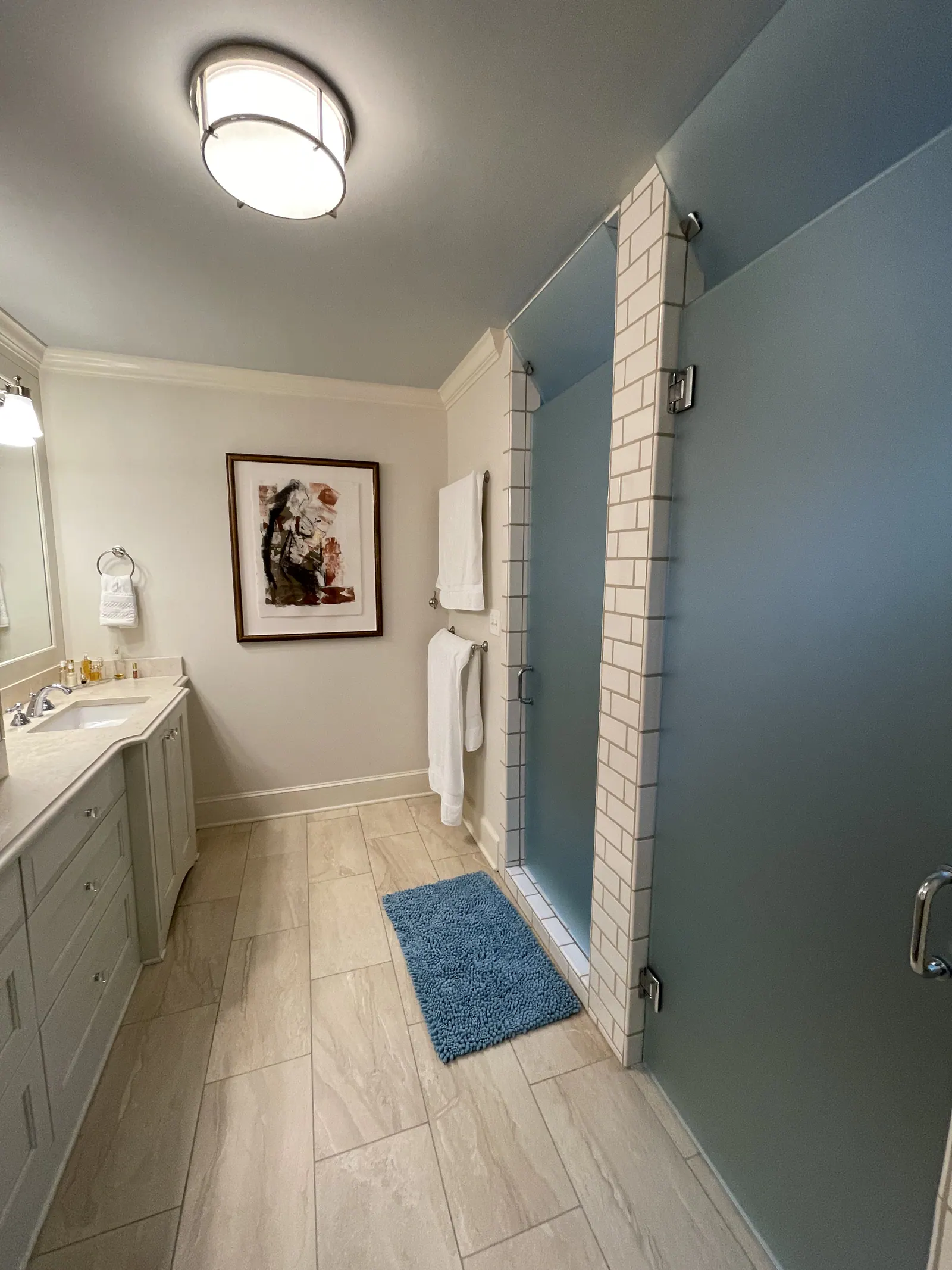 Before: Quail Hollow bathroom with a vanity and a subway tile shower behind a tinted glass door
