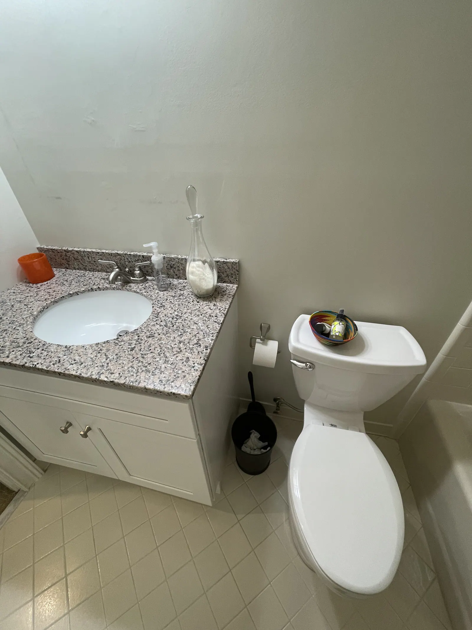 Before: Quail Hollow bathroom with a granite vanity, a white cabinet, and a tile floor