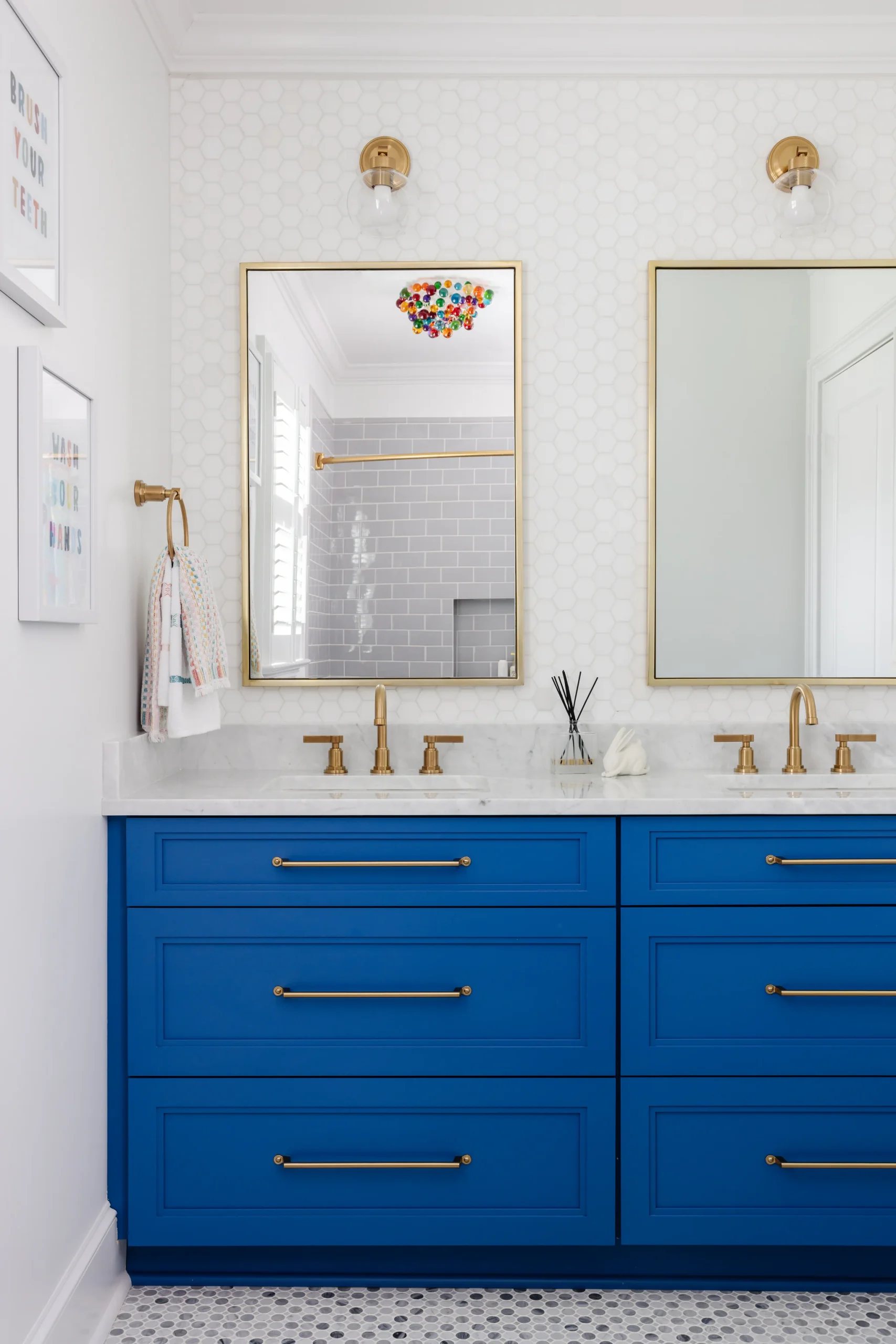 After: Quail Hollow bathroom with a blue double vanity, gold hardware, and honeycomb tile