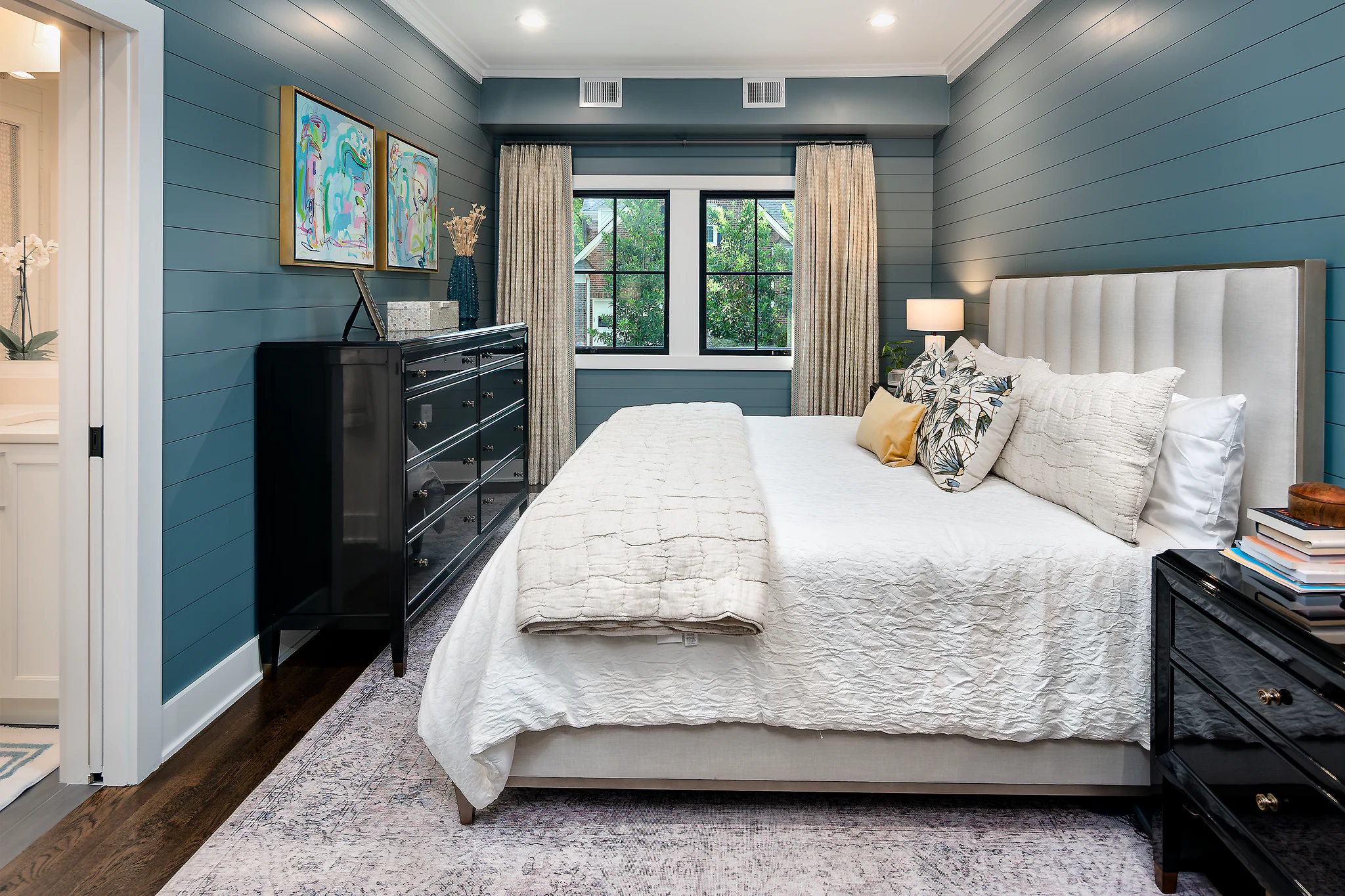 Bedroom in Providence Plantation with blue shiplap walls, white upholstered headboard, and dark wood furniture