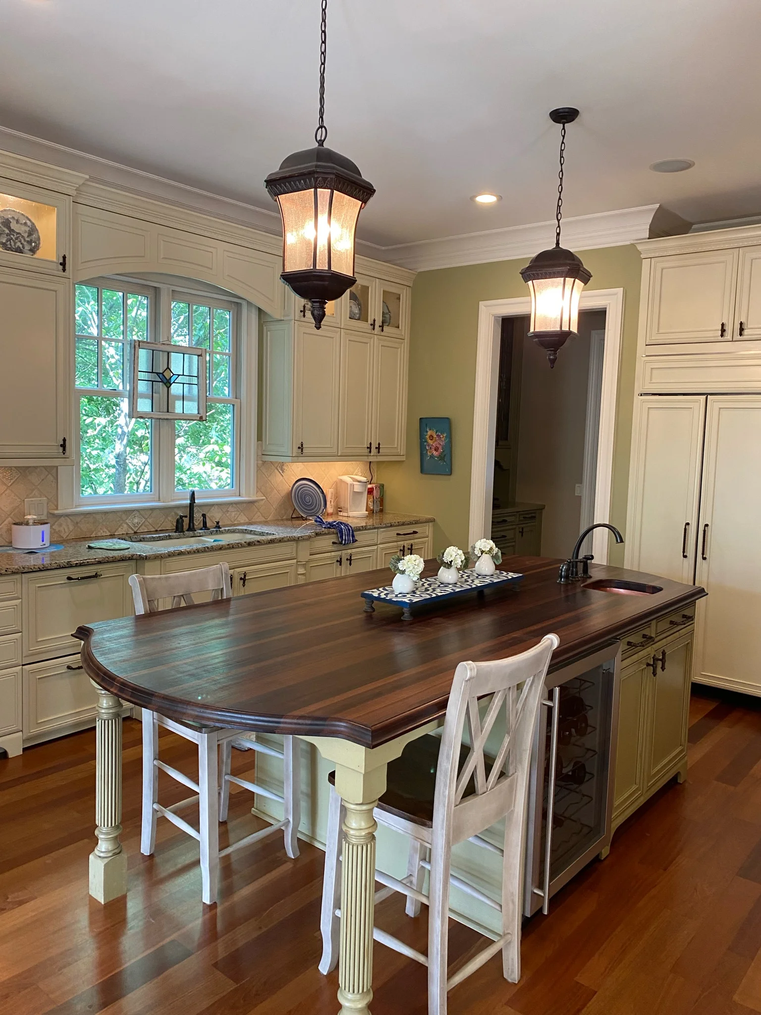 Whole-home remodel in Ballantyne Country Club, kitchen with cream cabinets, wood island, and pendants