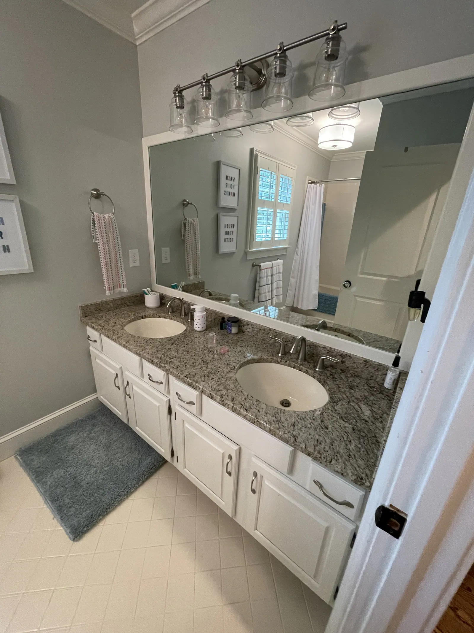 Before: Quail Hollow bathroom with a double vanity, a granite countertop, and white cabinets