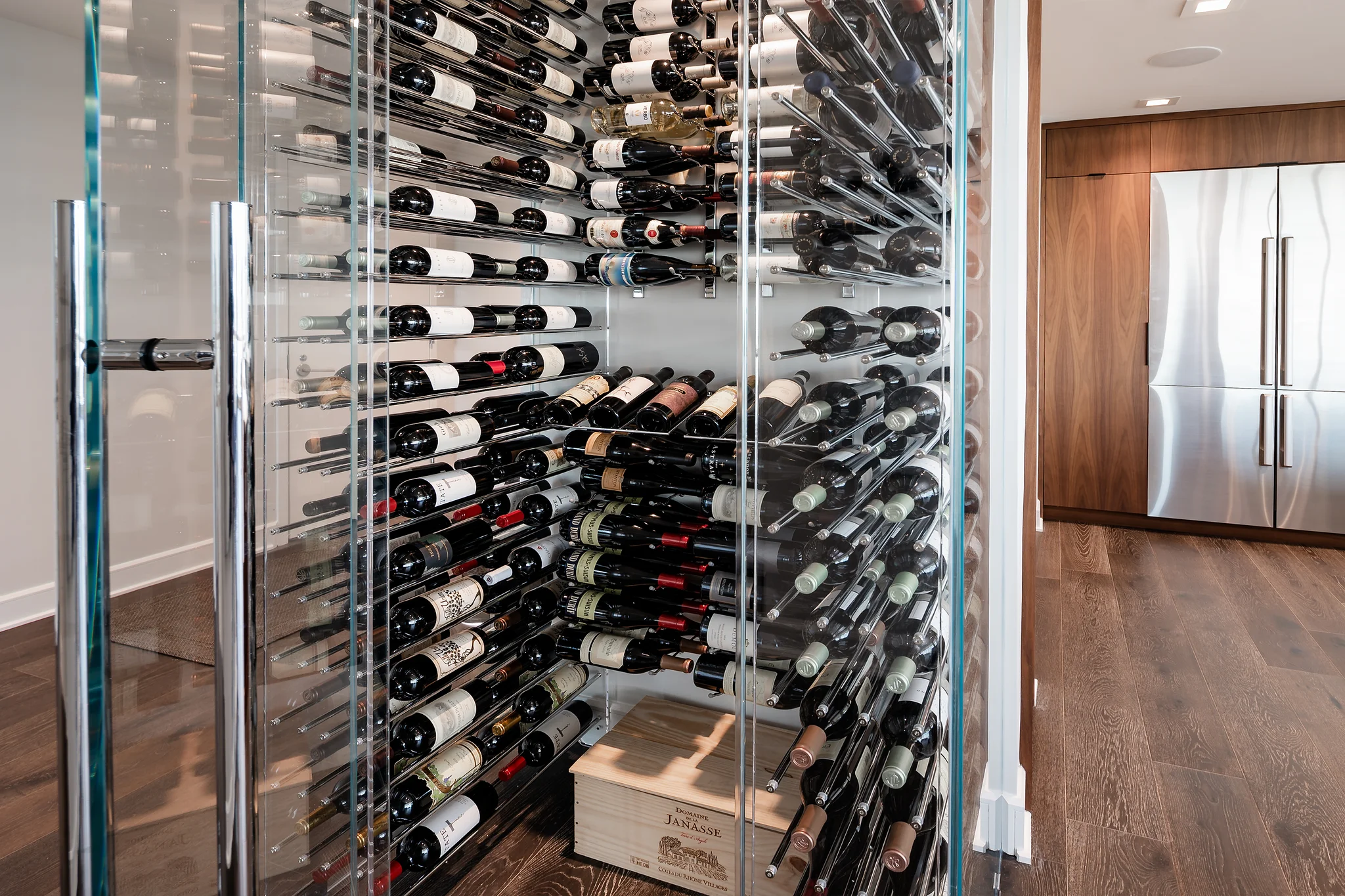 Penthouse remodel at The Arlington, glass wine cellar with metal racks, wood flooring, and a stainless steel refrigerator