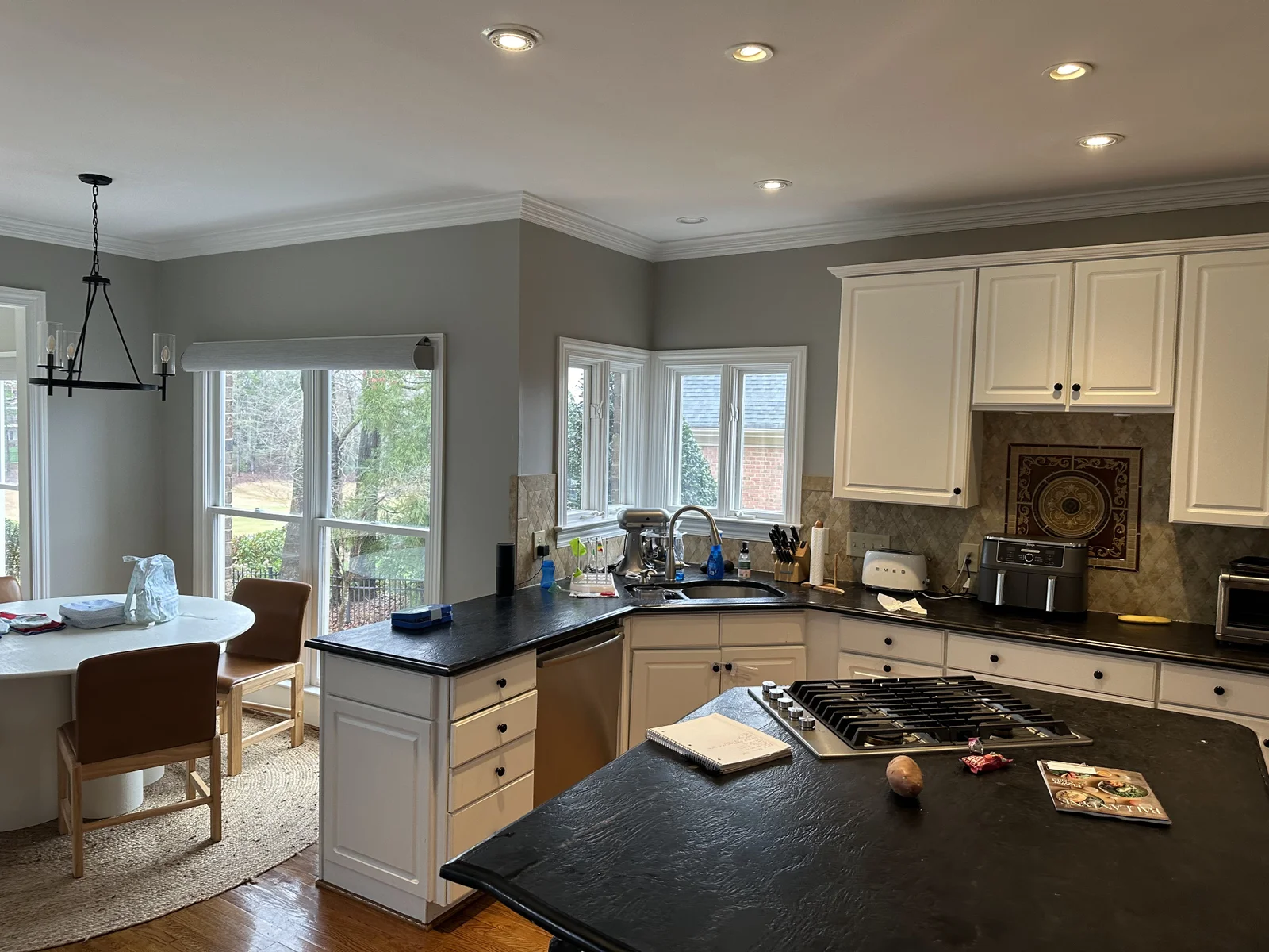 Kitchen remodel in Ballantyne Country Club with dark counters, white cabinets, and a gas range island