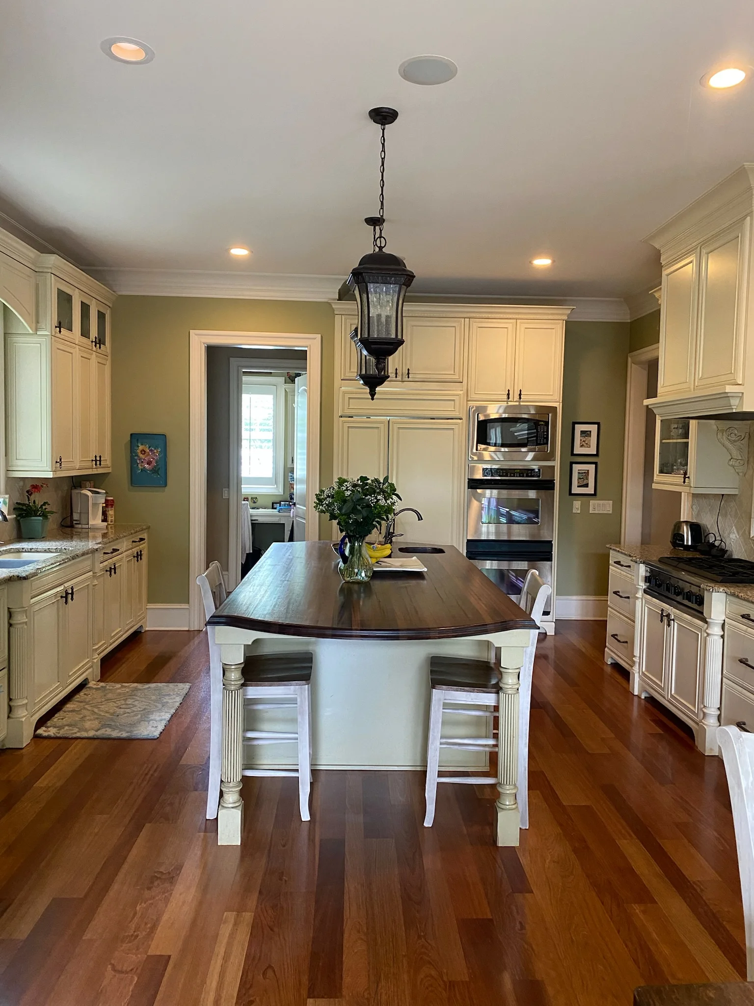 Before: Ballantyne Country Club kitchen with light cabinets, a dark wood island, and a pendant light