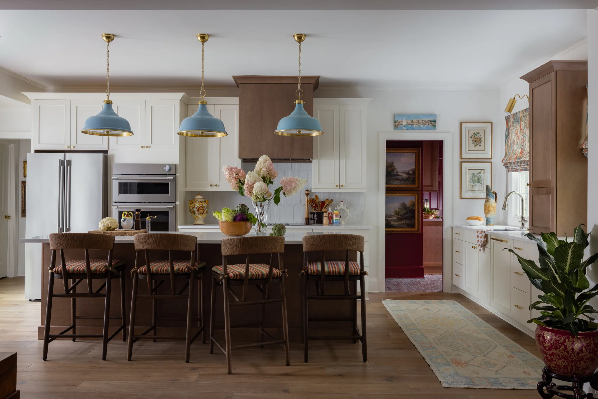 Kitchen remodel in Sedgefield with a brown island, blue pendant lights, and white perimeter cabinets