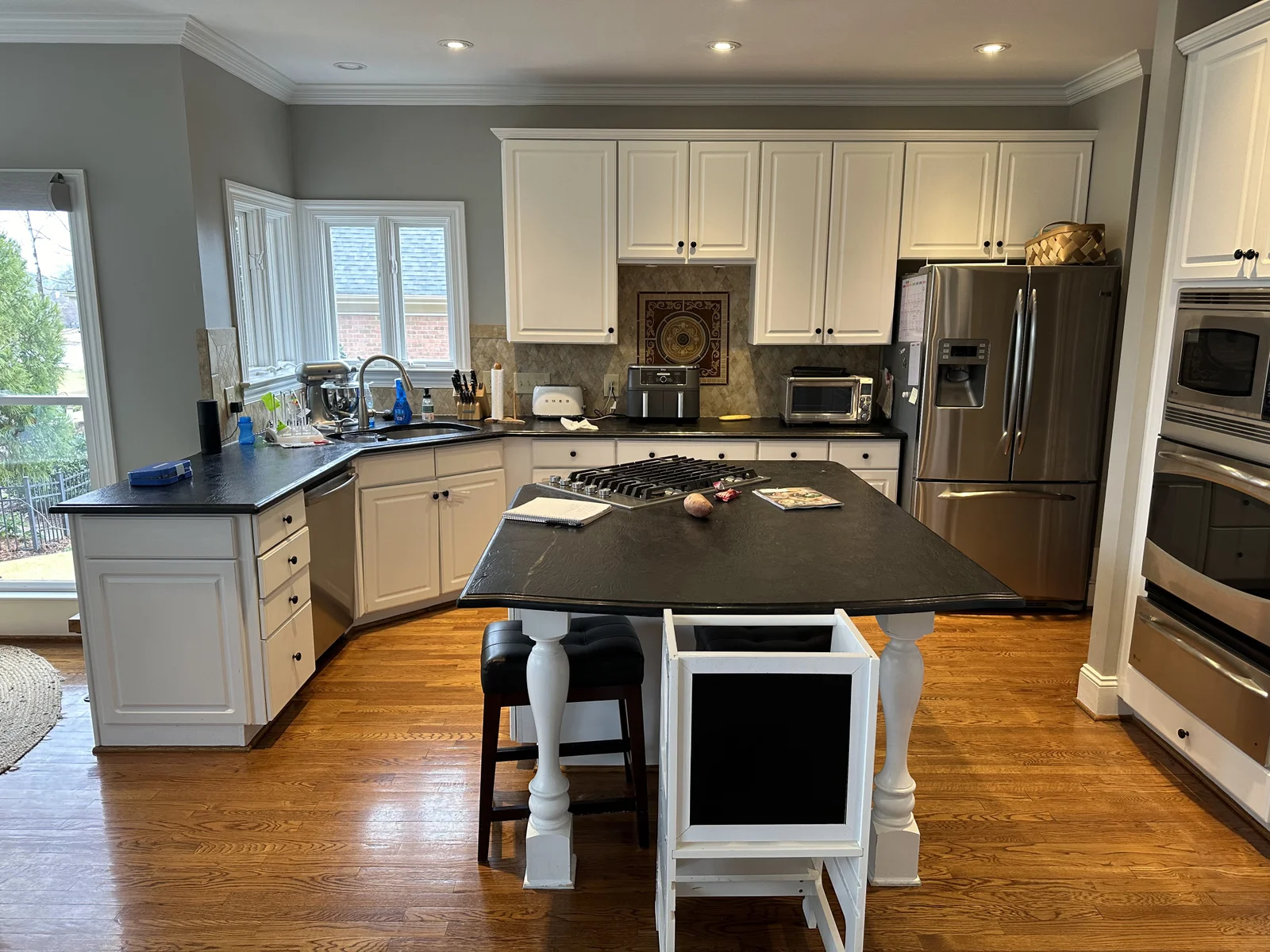 Before: Ballantyne Country Club kitchen with white cabinets, dark countertops, and wood floors