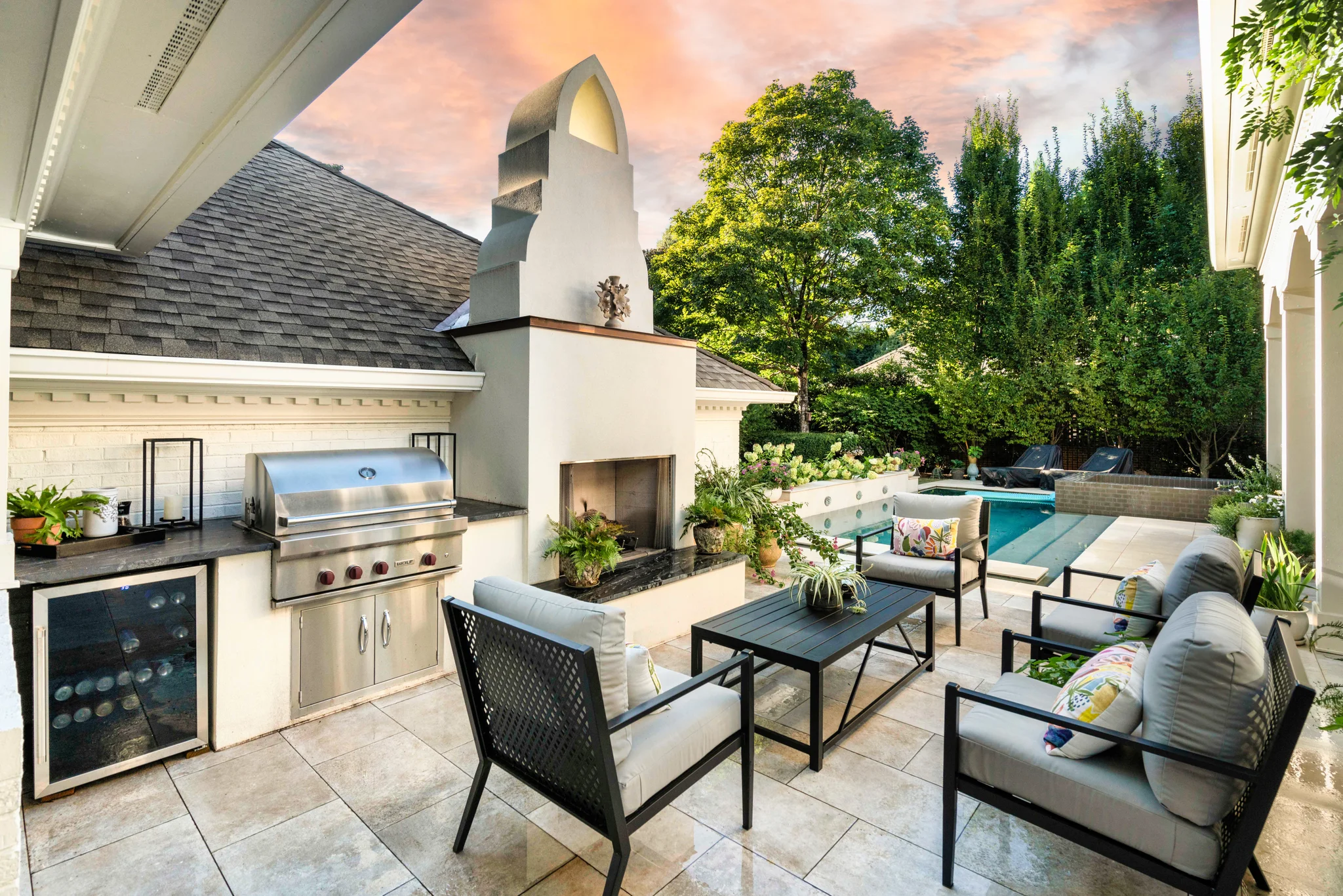 Outdoor living space with a built-in grill, fireplace, and patio seating around a pool