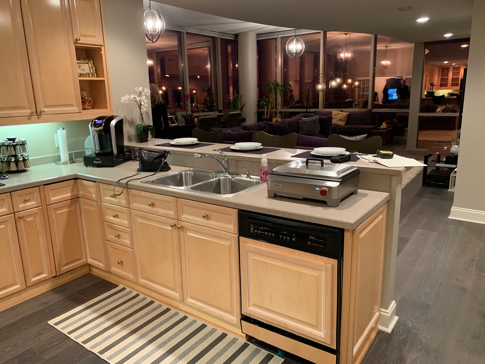 Penthouse kitchen with maple cabinets, dark wood floors, and a kitchen island with a double sink