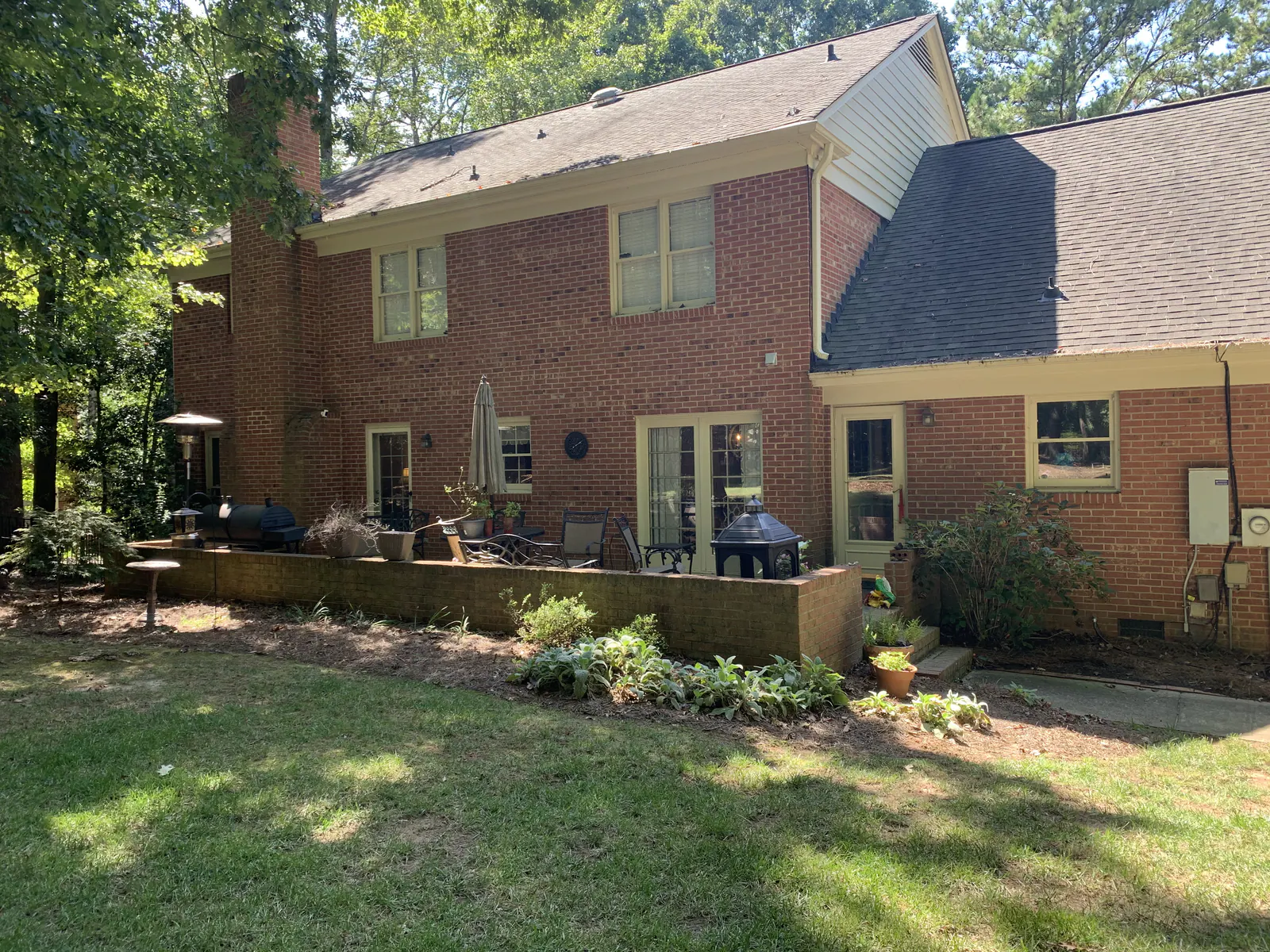 Before: Red brick Providence Plantation home with a backyard patio, outdoor seating, and a grill