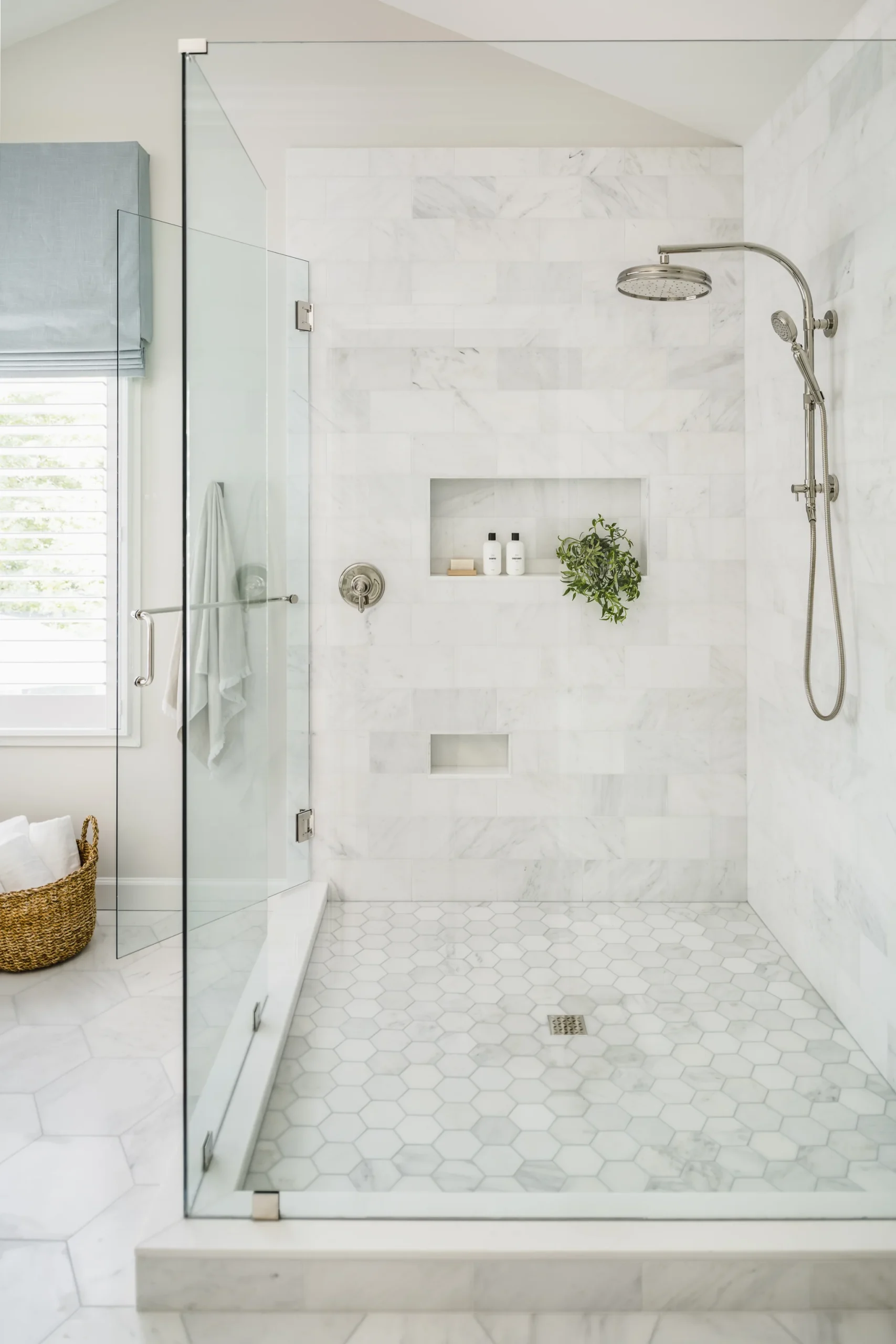Walk-in shower with white marble subway tile walls, hexagon tile floor, and glass enclosure