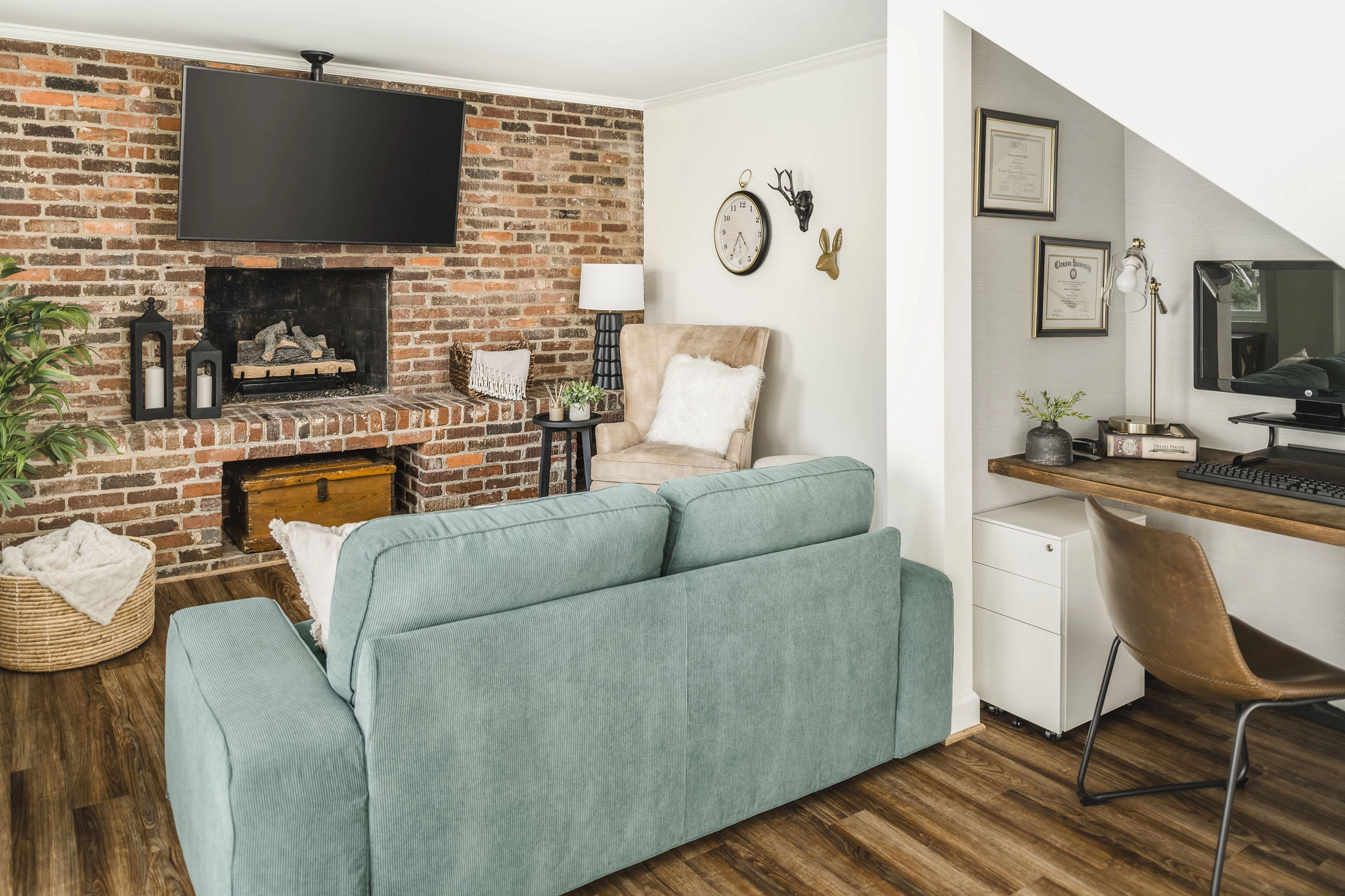 Finished basement with brick fireplace, light blue sofa, and under-stairs home office in Charlotte, NC