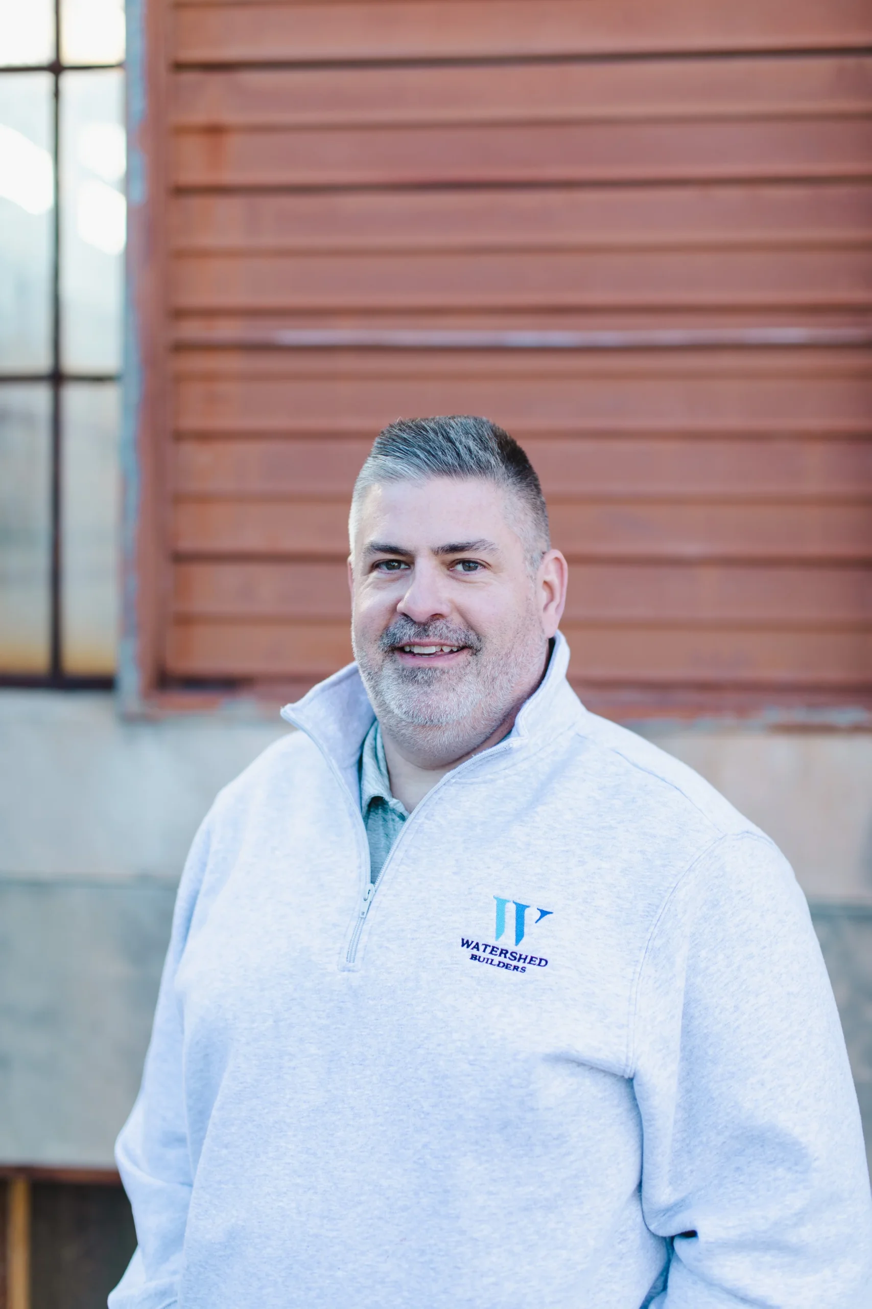 Marc Bernash, Project Manager for Watershed Builders, smiling in a gray quarter-zip sweatshirt