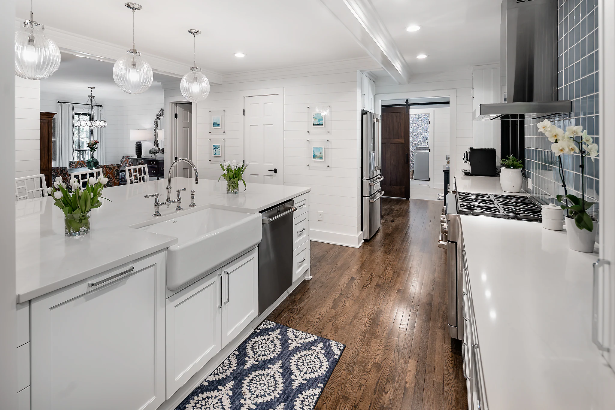 Whole-home remodel in Providence Plantation, white kitchen with shiplap walls, quartz island, and wood floors