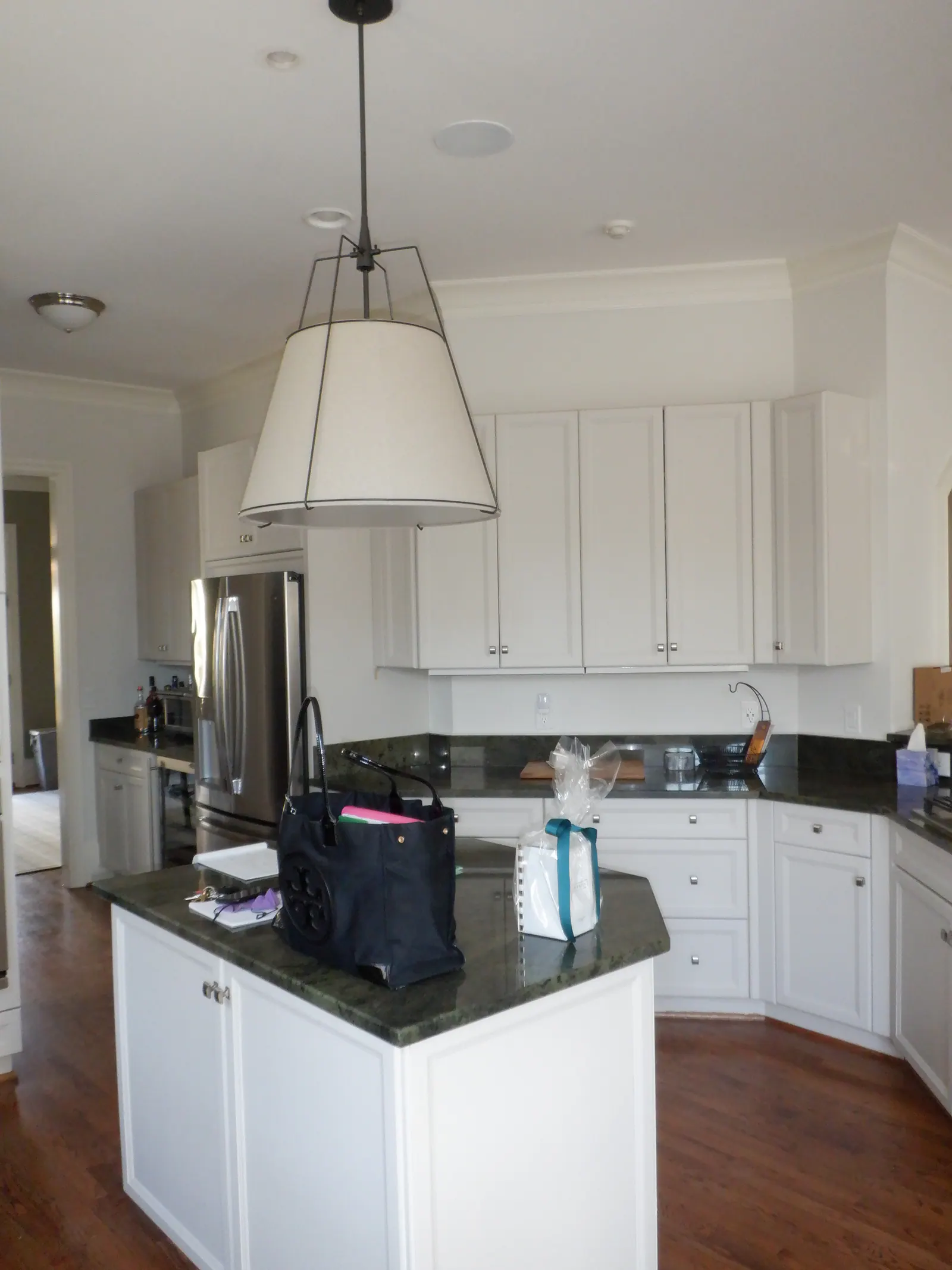 Before: Heydon Hall kitchen with white shaker cabinets, dark granite, and a large pendant light