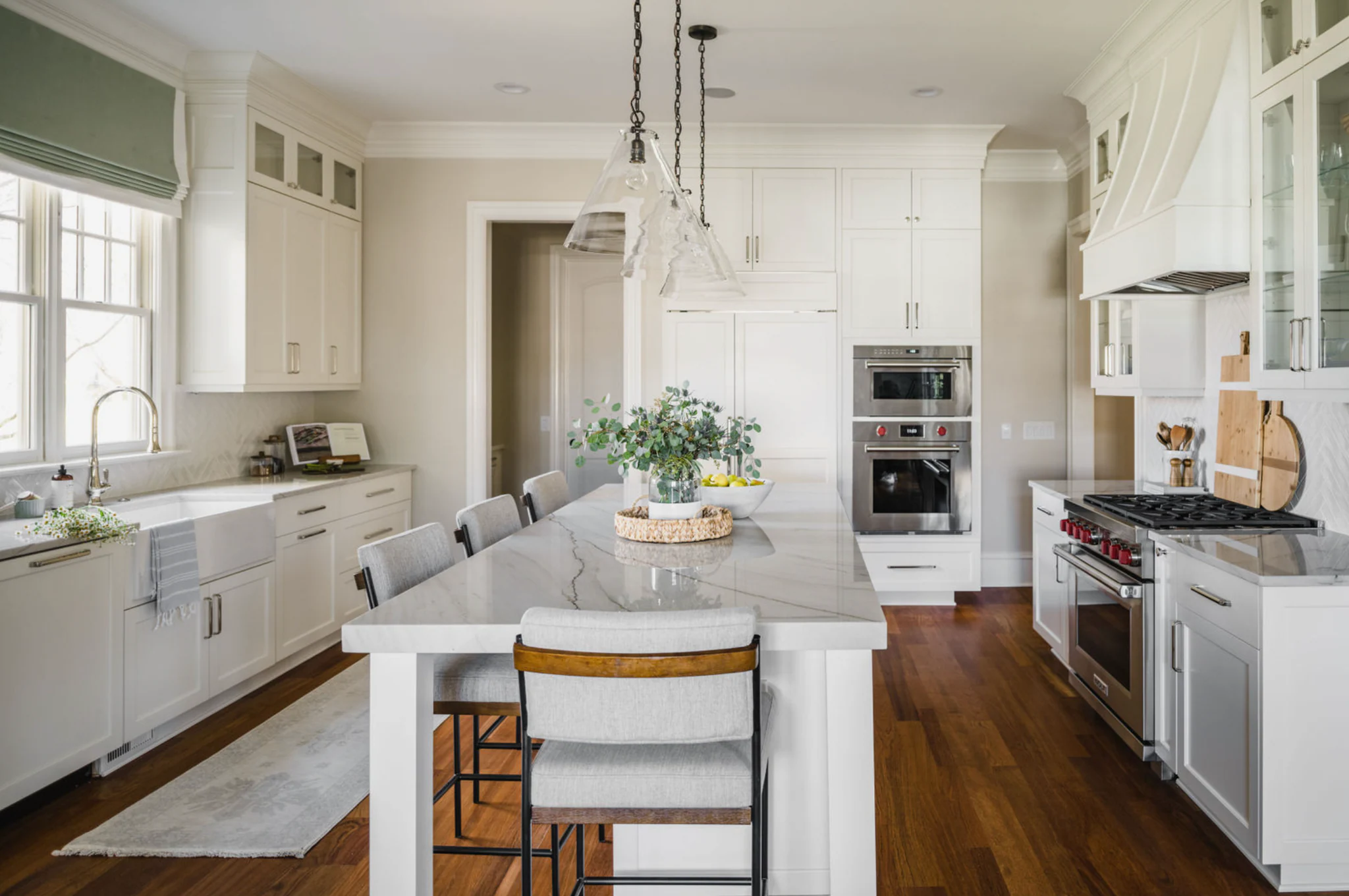 After: White kitchen with a marble island and farmhouse sink in a Ballantyne Country Club whole-home remodel