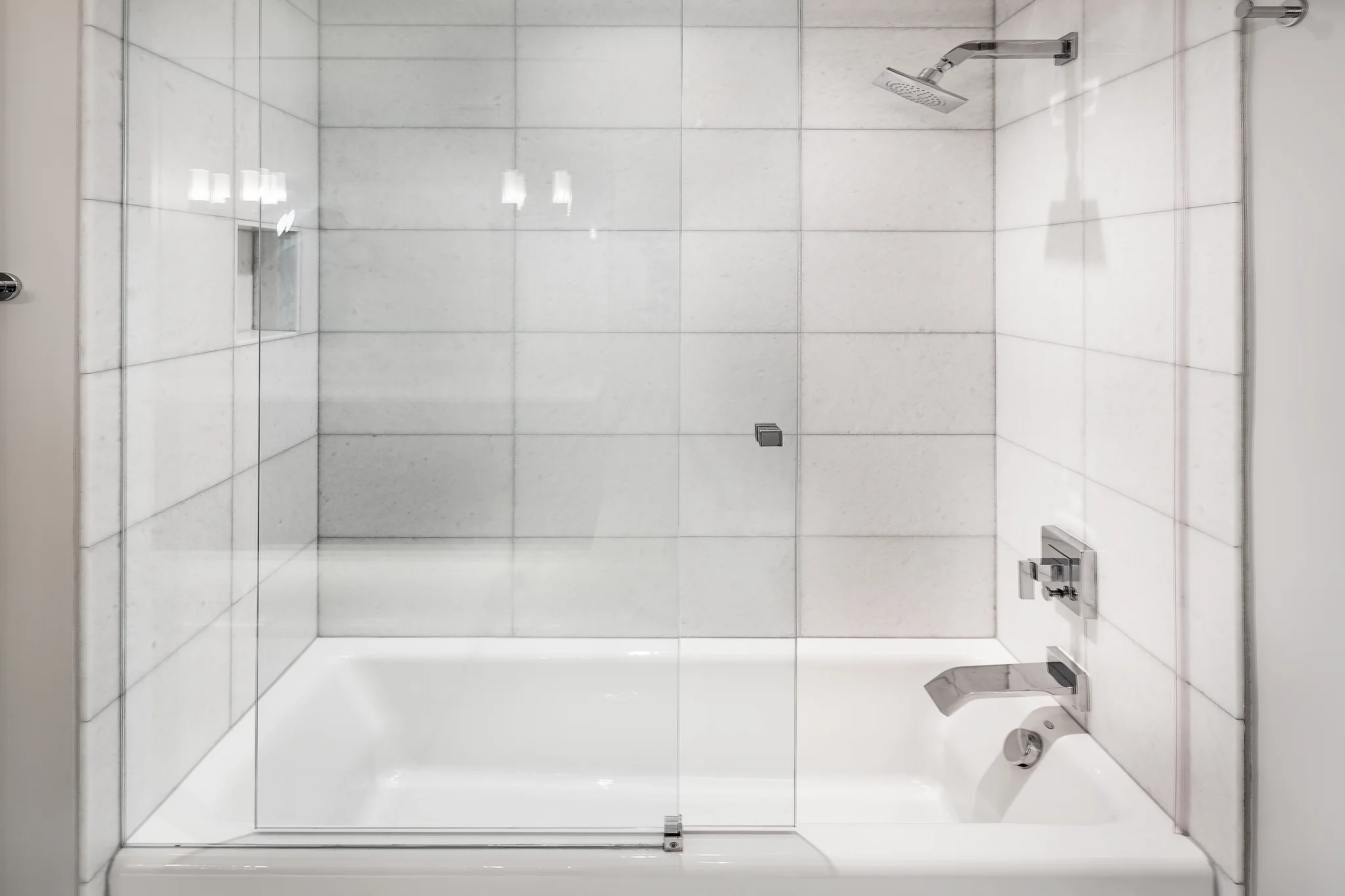 Penthouse remodel, white tiled shower and tub with glass enclosure, chrome fixtures