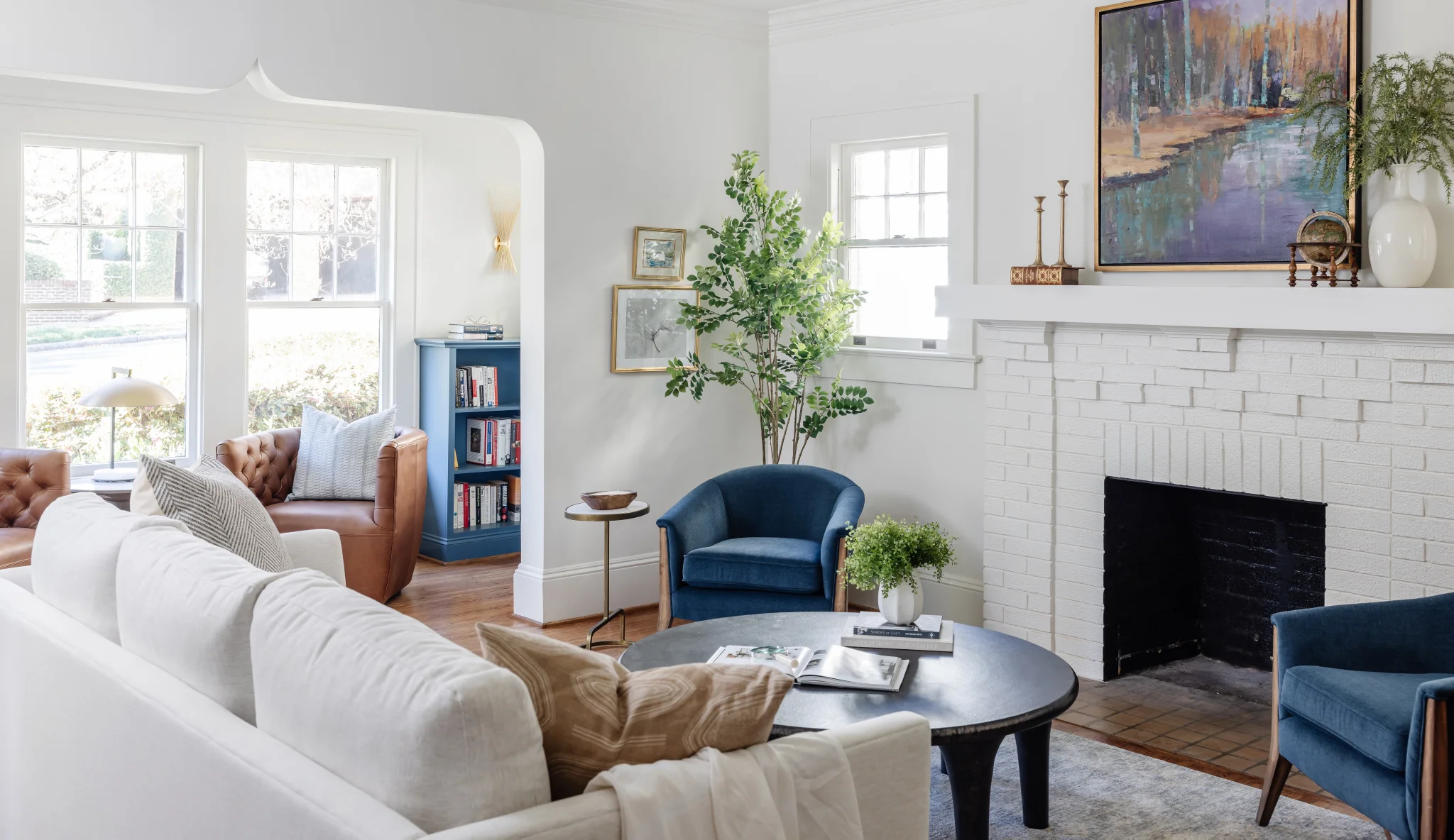 After: Dilworth living room with a white sofa, blue chairs, and a white brick fireplace