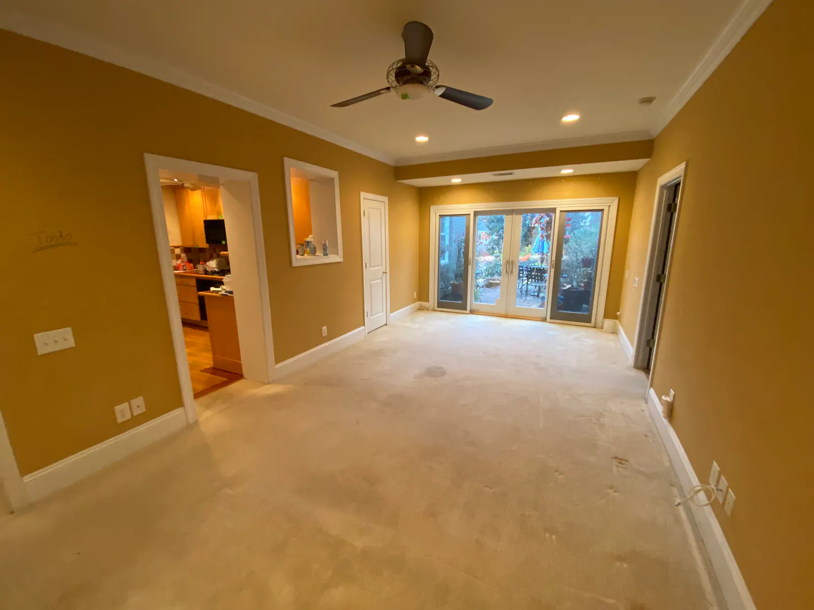 Sedgefield whole-home remodel, empty living room with yellow walls, carpet, and French doors